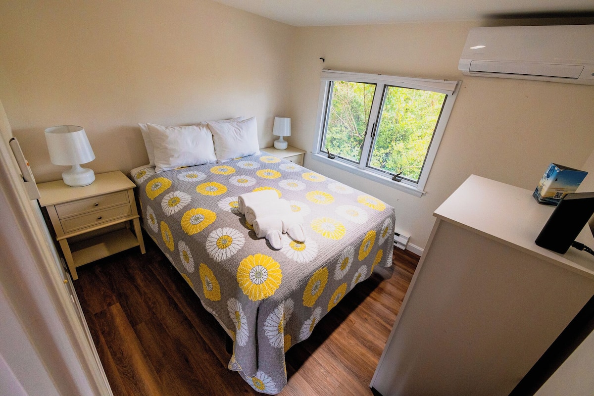 A bedroom with a bed, nightstands, a window, and an air conditioner.