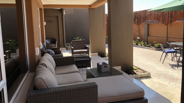 Un espacio al aire libre con mobiliario de mimbre y una mesa de vidrio.