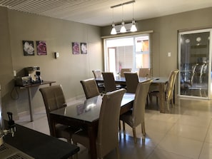 Un comedor con una mesa grande y sillas, una cafetera y obras de arte colgadas en la pared.