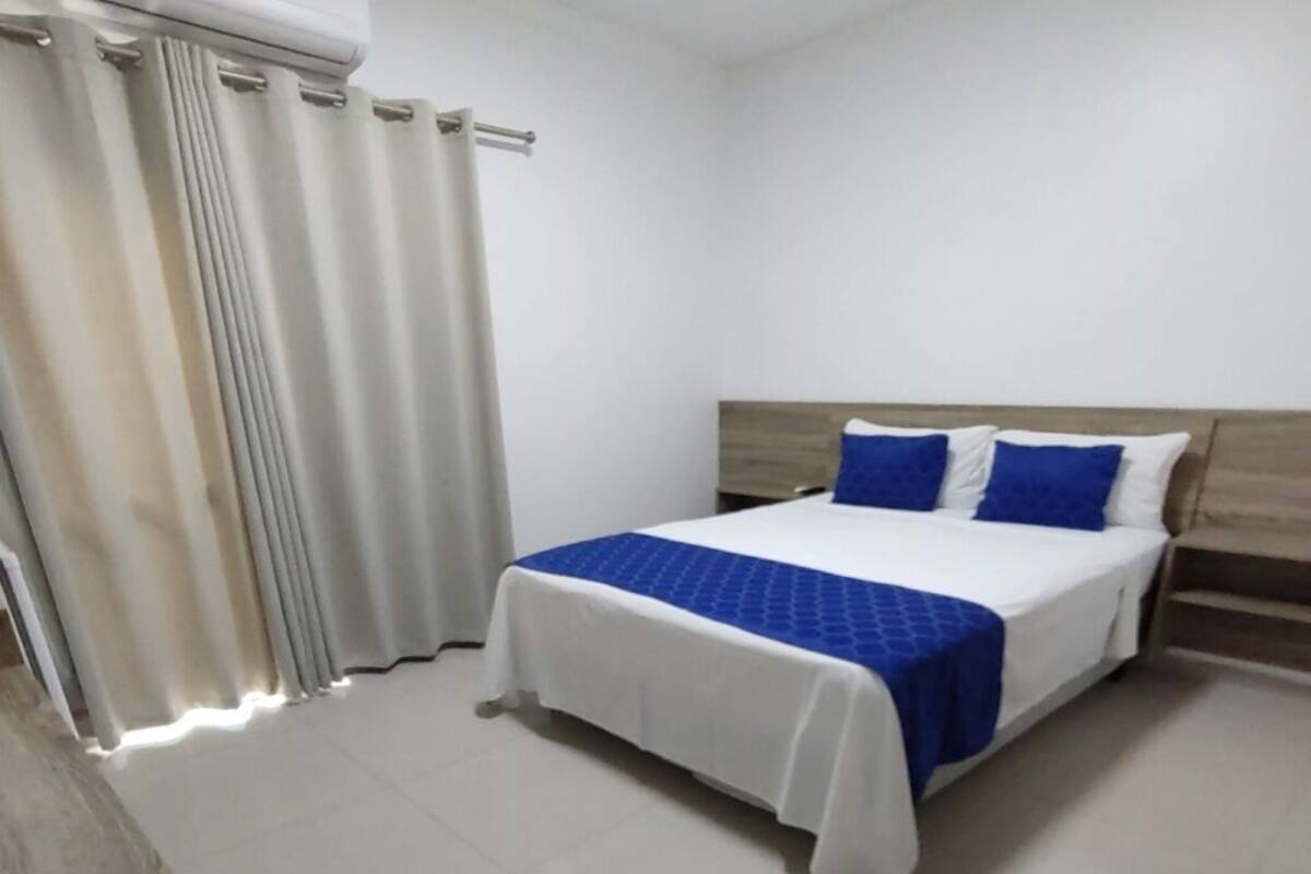Una habitación de hotel con cama, cortinas y ventana.