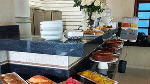 Un mostrador de buffet con diversos alimentos, como frutas y pasteles, y un dispensador de agua.
