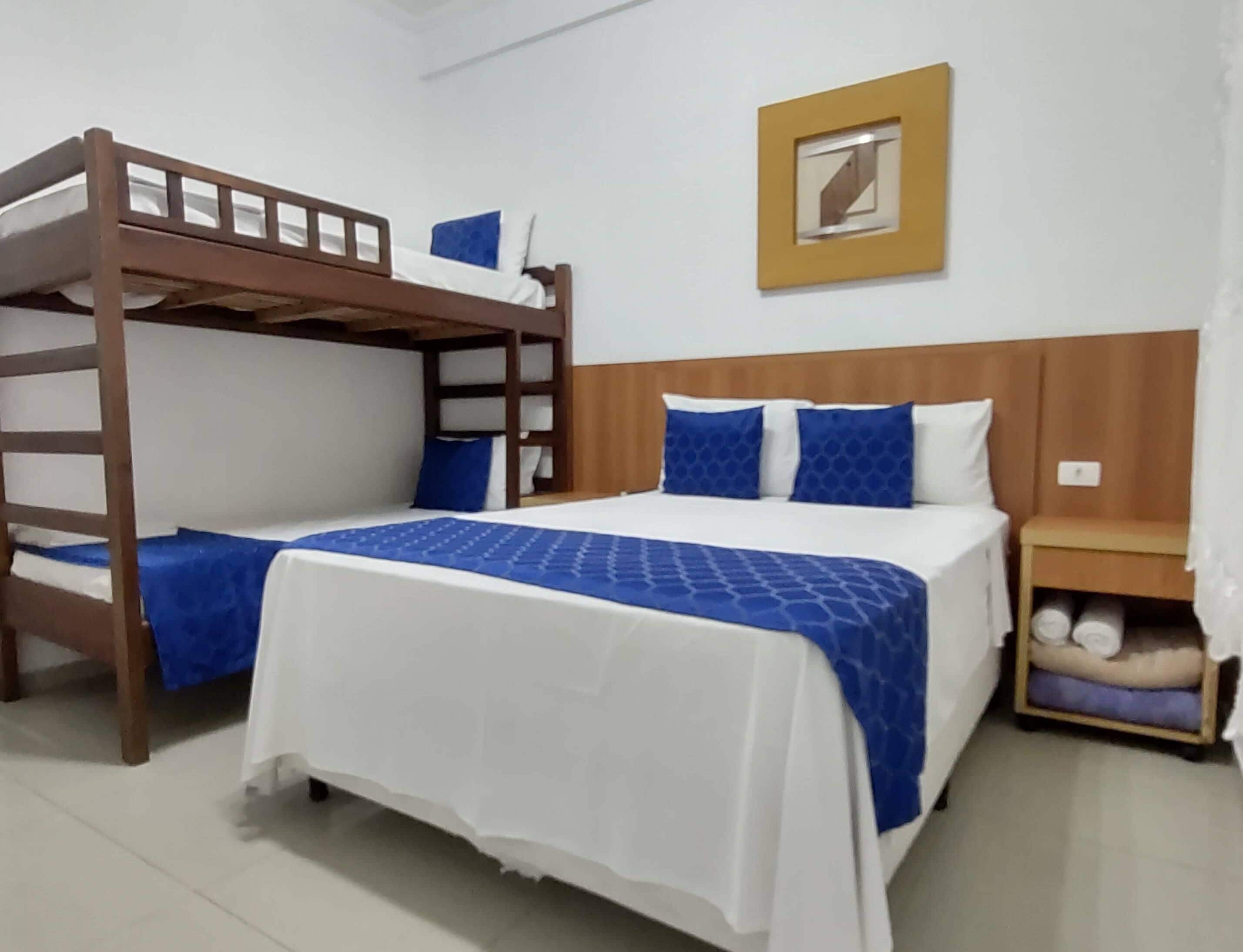 A bunk bed room with a wooden headboard, a bedside table with a lamp, and a wall-mounted picture.
