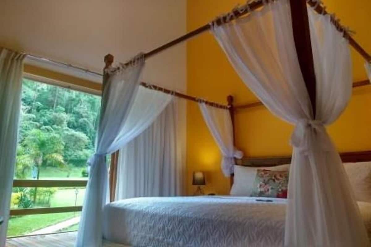 Un lit à baldaquin avec des draps blancs, une tête de lit en bois et un ciel de lit.