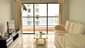 Un soggiorno con divano, tavolino, mobile TV e balcone con vista sugli edifici.