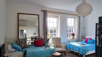 Een slaapkamer met twee bedden, een stoel, een tafel, een spiegel en een hanglamp.