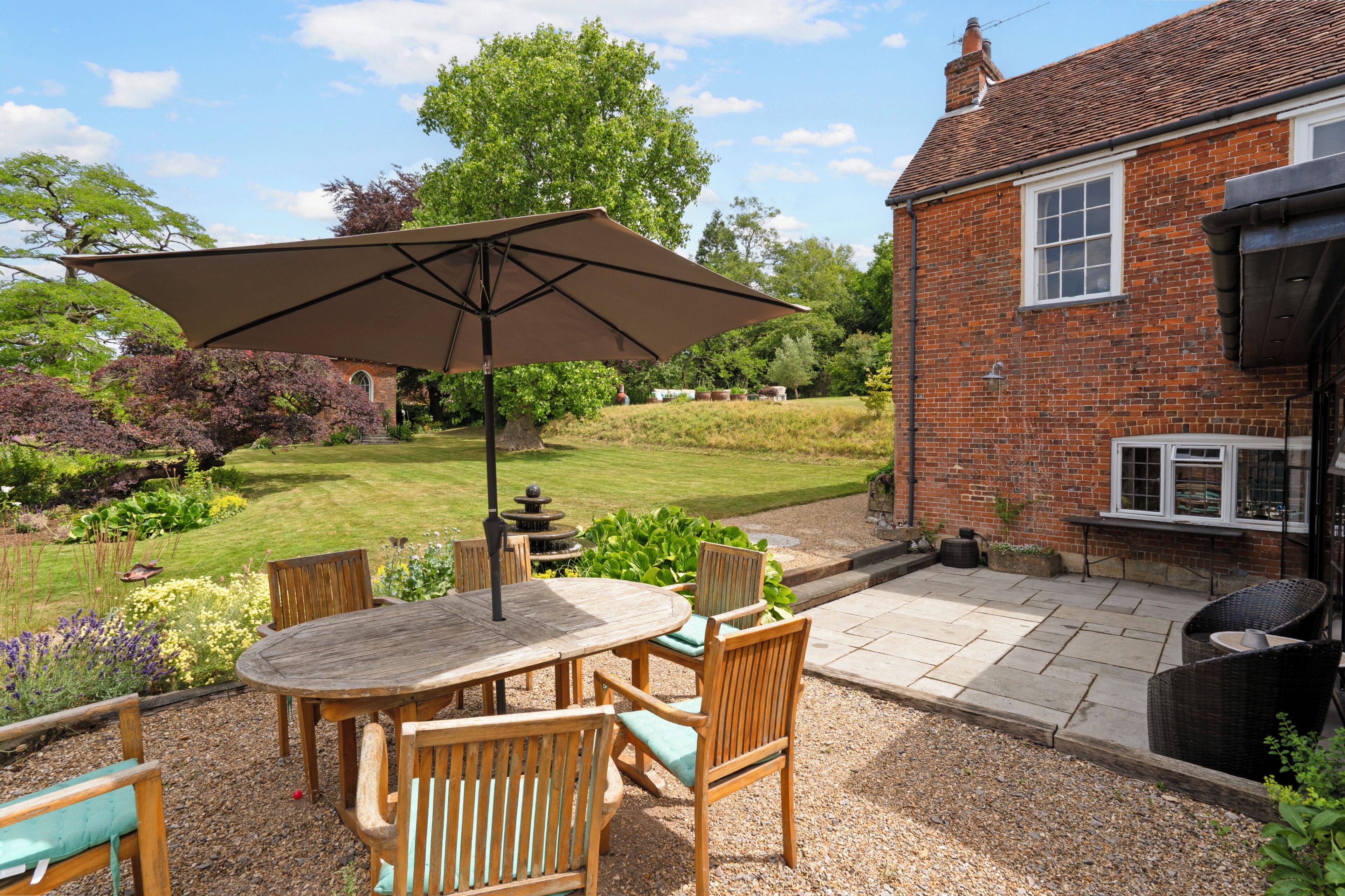 A patio with a table and chairs, a large umbrella, and a brick building in the background.