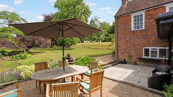 A patio with a table and chairs, a large umbrella, and a brick building in the background.
