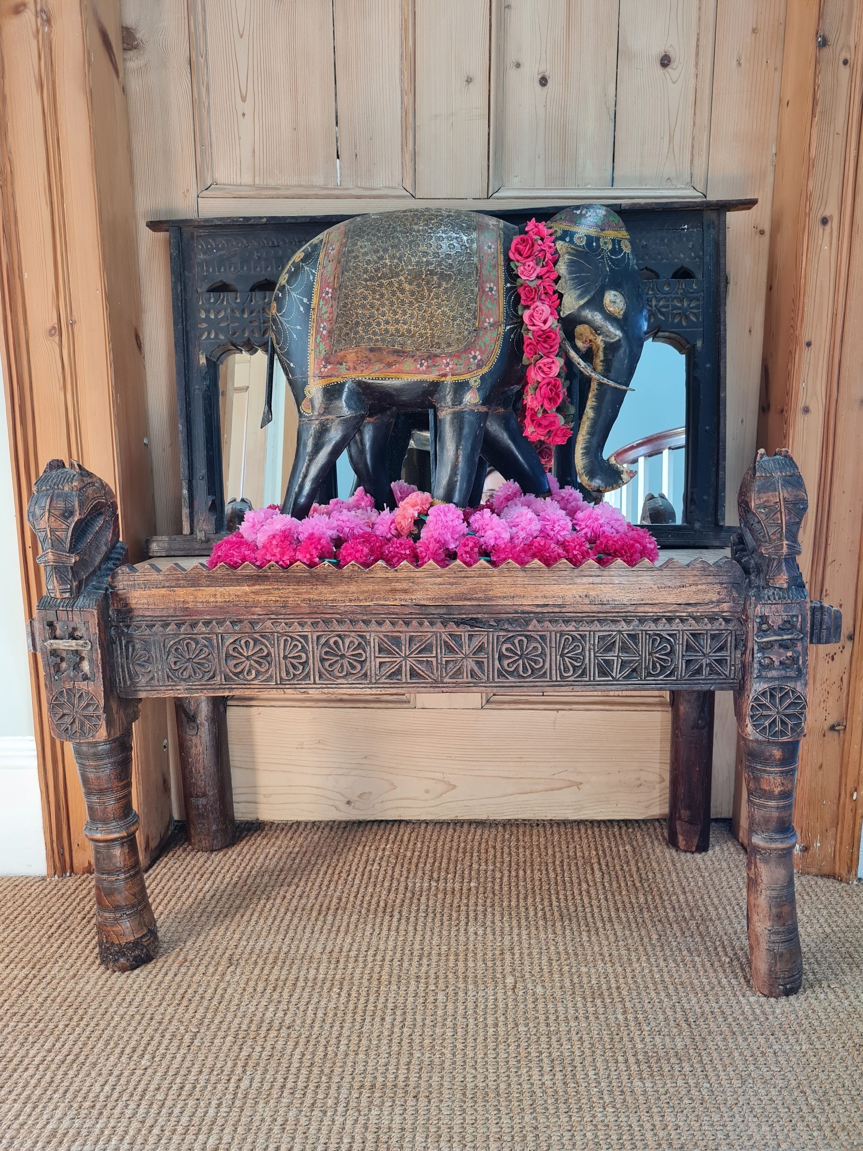 A wooden bench with intricate carvings and a decorative elephant head.