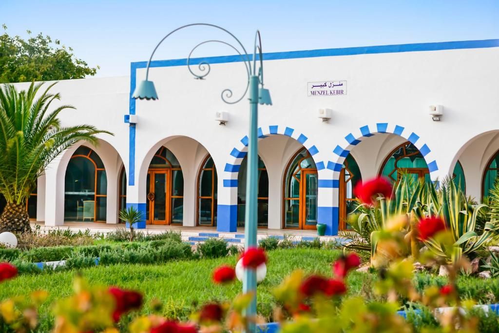 Un edificio con fachada blanca, detalles en azul y ventanas arqueadas.