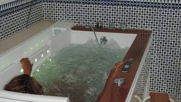 A bathtub with a wooden edge, a faucet, and a control panel.