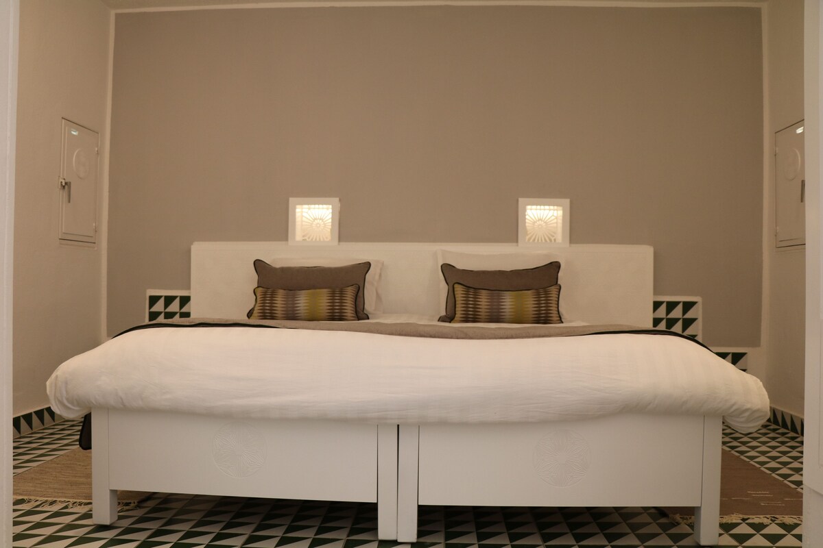 A bed with a white headboard, two pillows, and two bedside lamps.