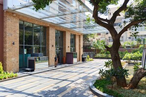 Stunning glass-enclosed entrance with a metal frame, set amidst a lush urban landscape.