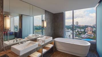A modern bathroom with a large bathtub, two sinks, and a large mirror.