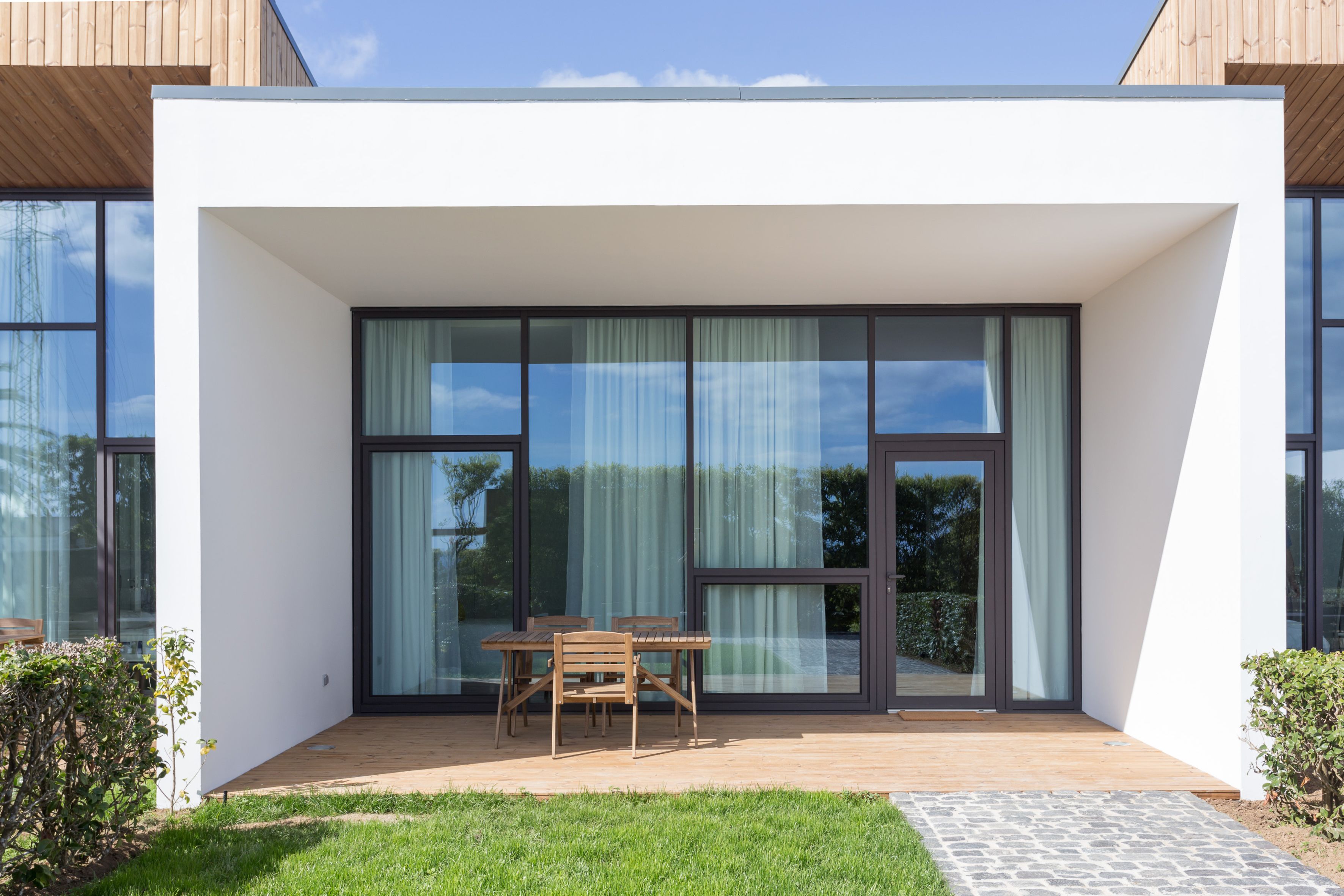 Une maison moderne dotée d’un patio, d’une table à manger et de chaises.