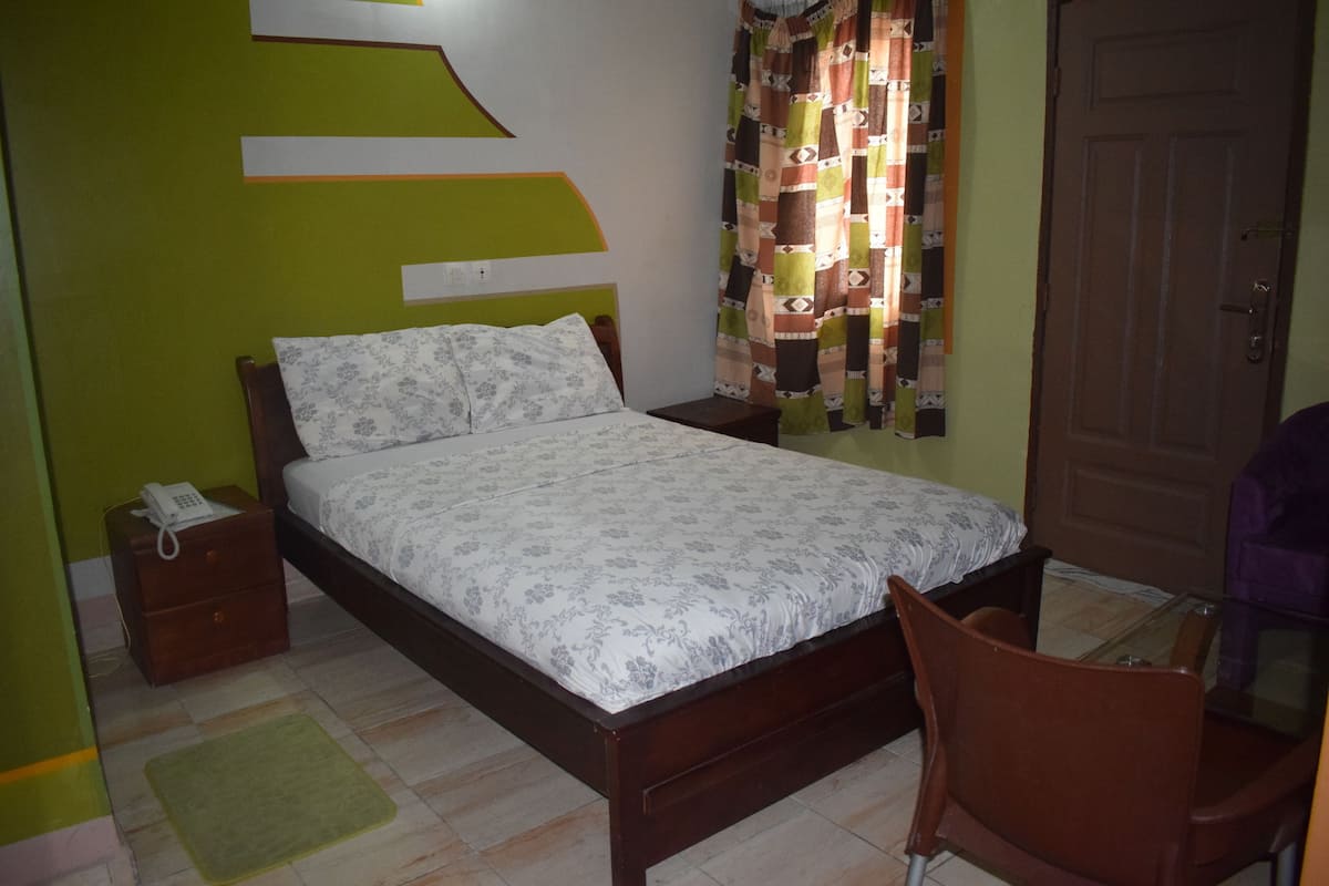 A bedroom with a bed, bedside tables, a chair, and a door.