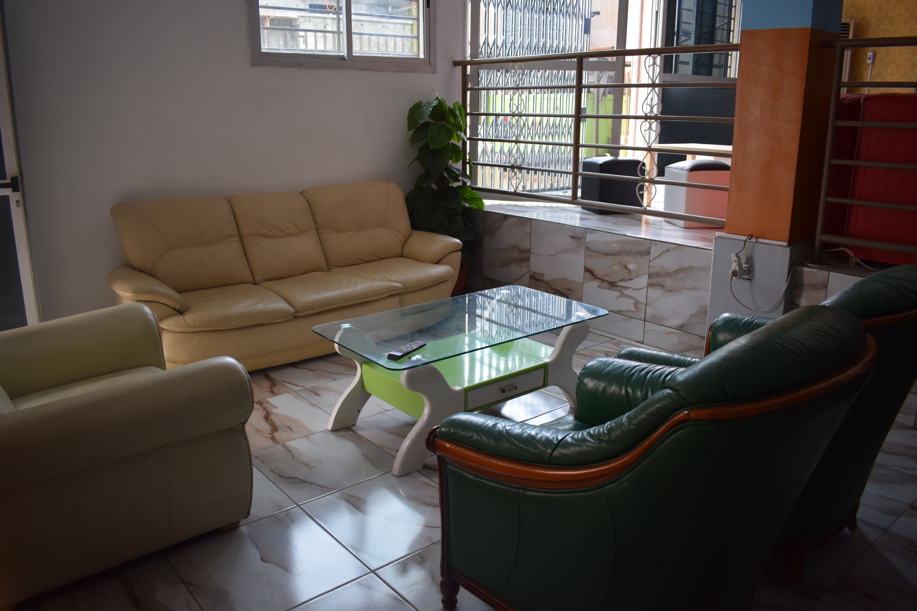 A living room with a beige sofa, a glass coffee table, and a green armchair.