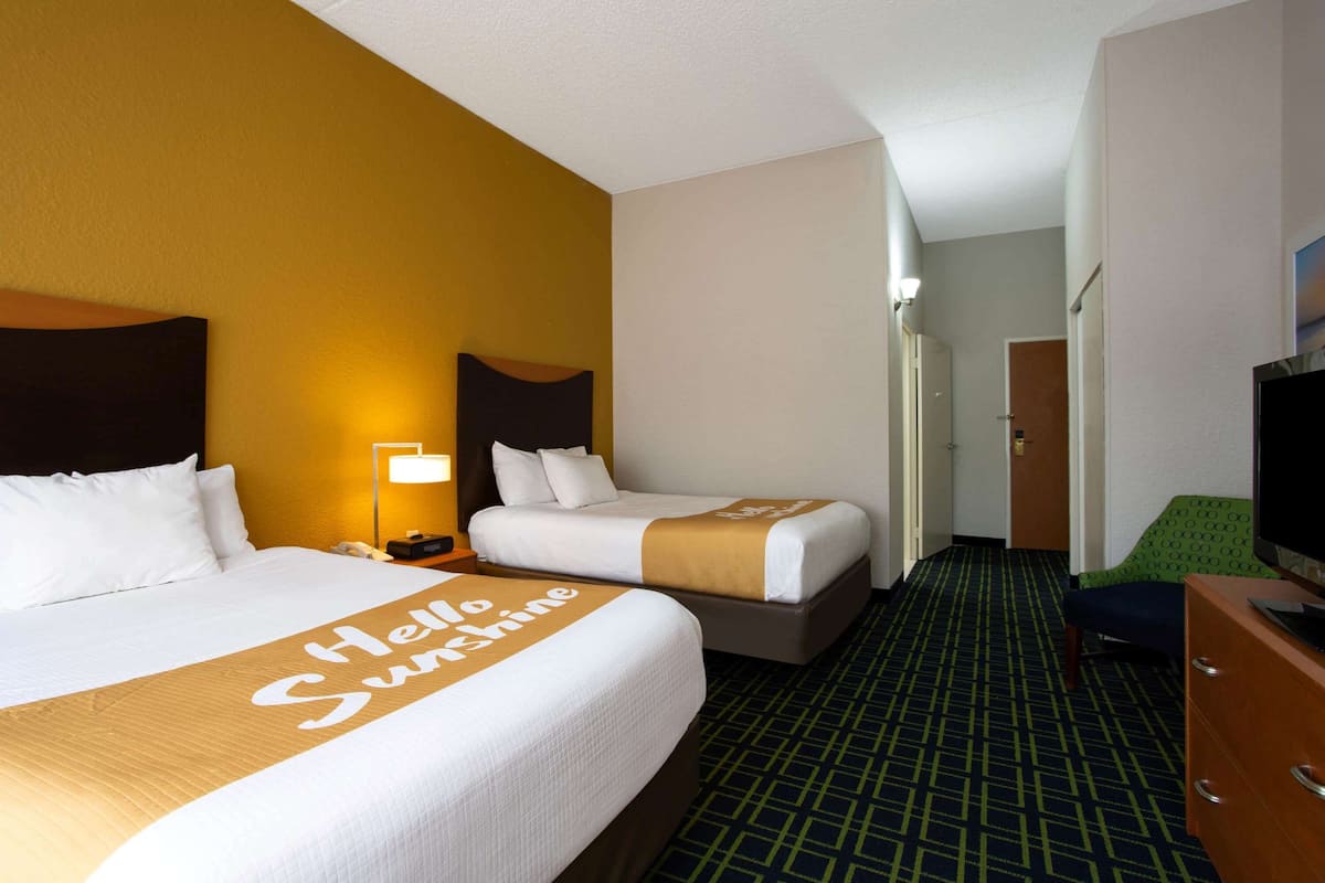 Une chambre d’hôtel avec deux lits, une télévision et un bureau.