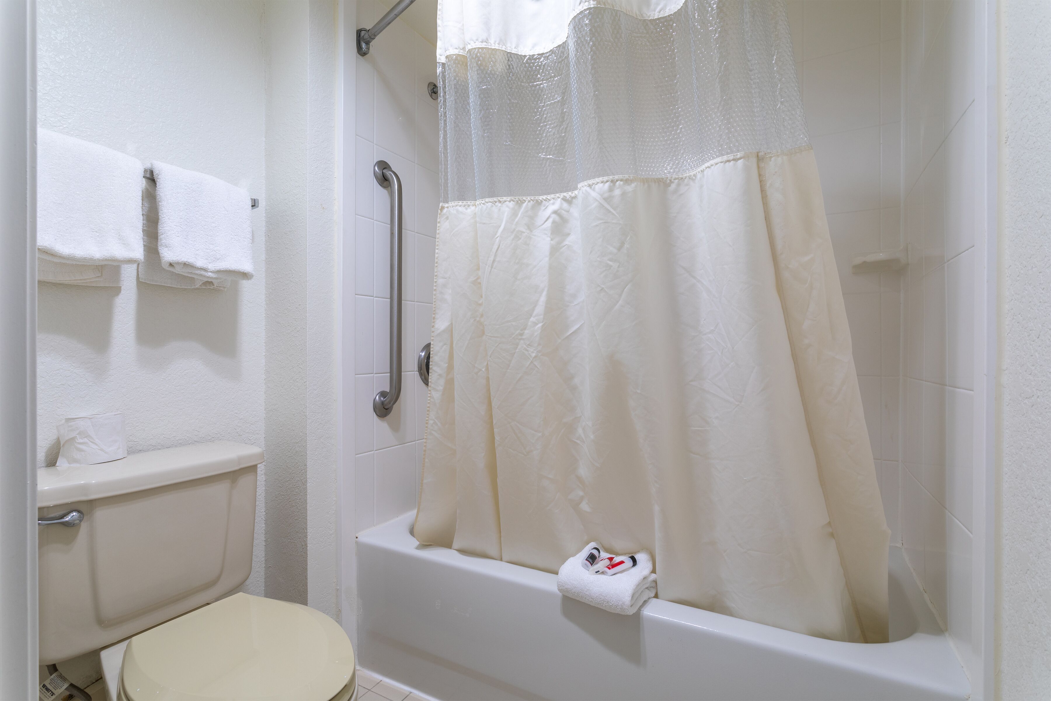 A bathroom with a bathtub, a toilet, and a shower curtain.
