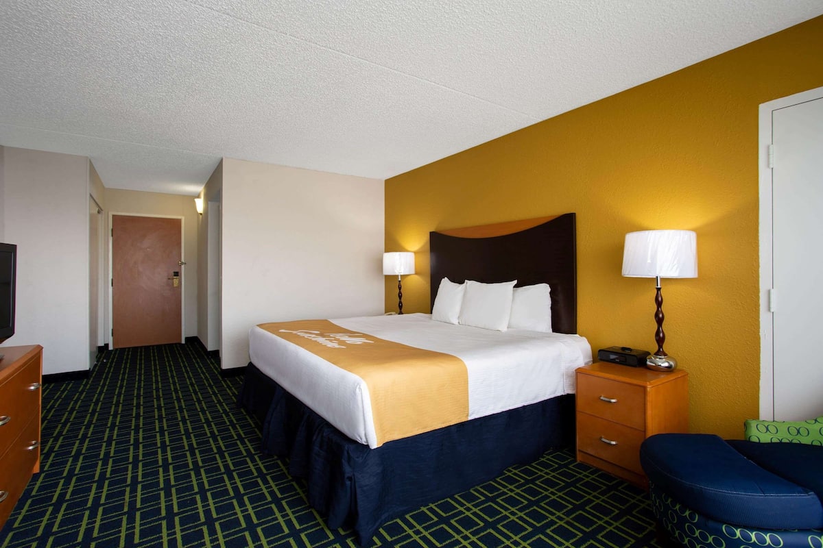 Une chambre d’hôtel avec un grand lit, un bureau, une chaise et un téléviseur.
