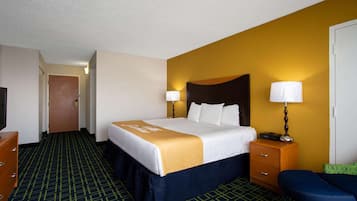 A hotel room with a large bed, a desk, a chair, and a TV.