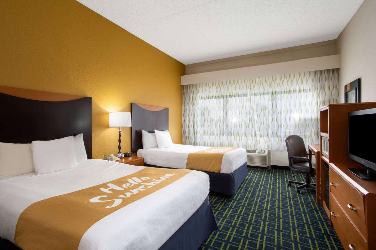 Une chambre d’hôtel avec deux lits, une télévision, un bureau et une chaise.