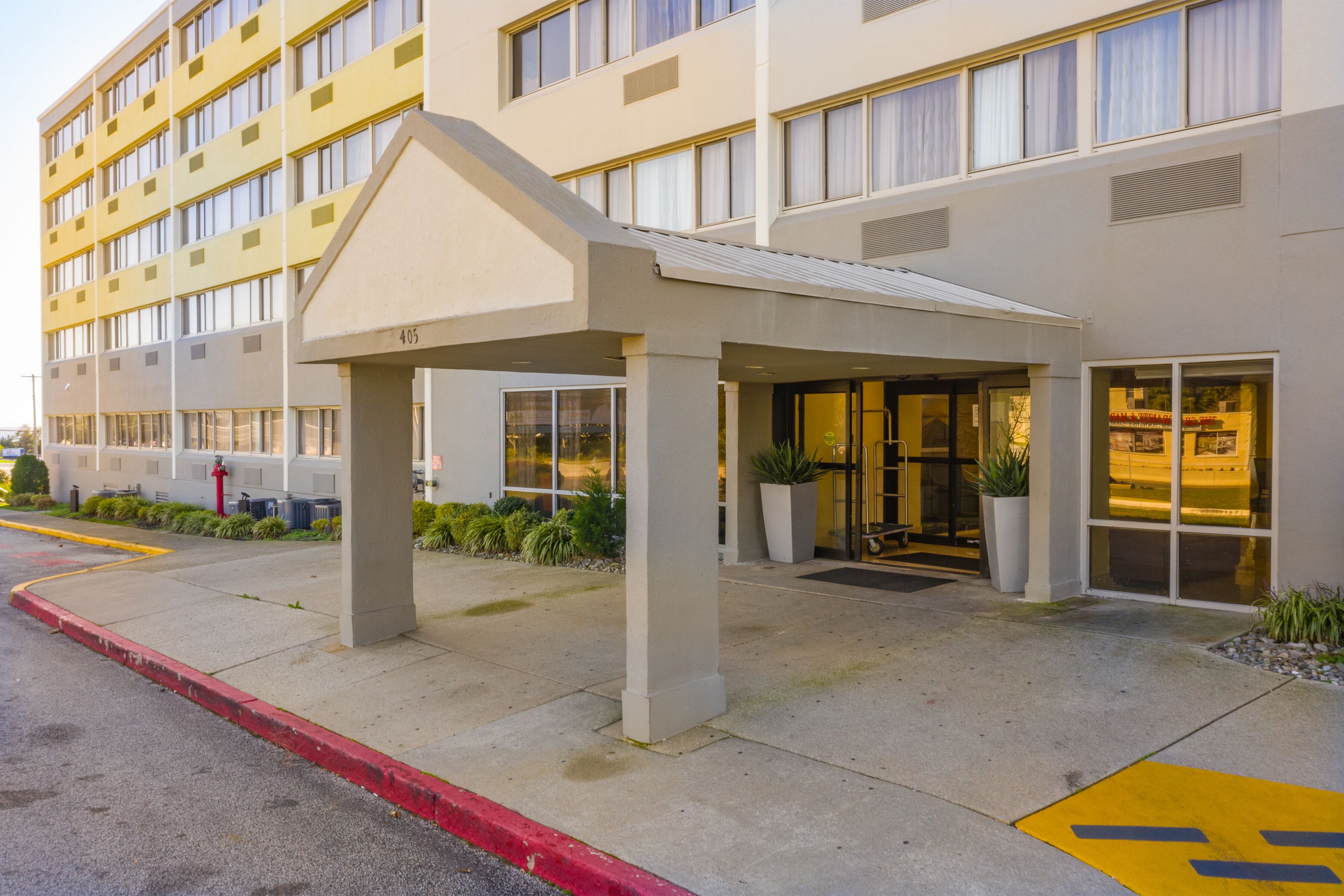 A hotel entrance with a covered walkway, a large entrance door, and a number '405' sign.