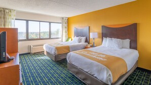 Een hotelkamer met twee bedden, een televisie en een raam met gordijnen.