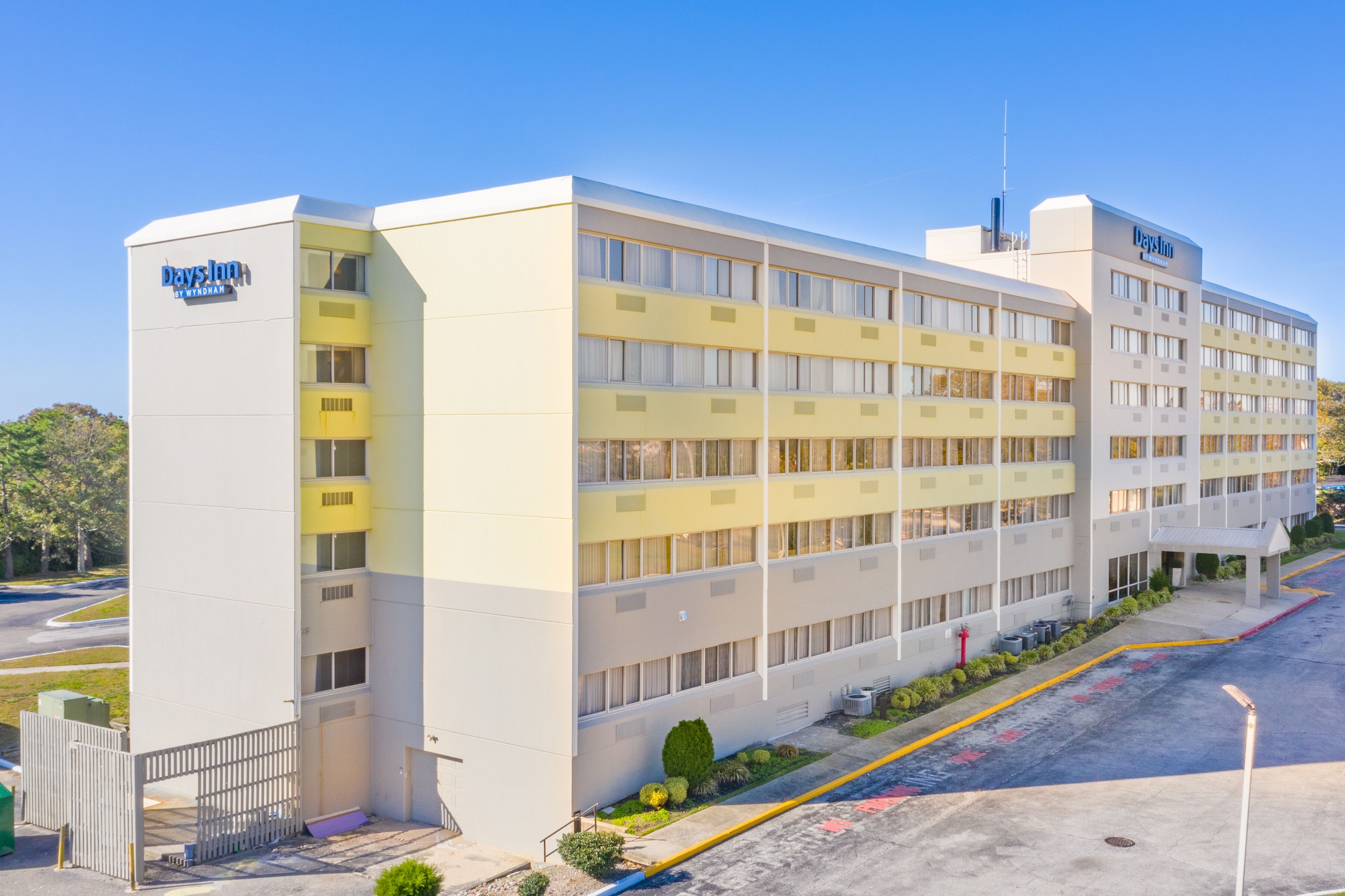A Days Inn with a modern design, featuring a flat facade, multiple balconies, and a parking area with marked spaces.