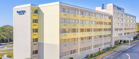 Un Days Inn con diseño moderno, que presenta una fachada plana, varios balcones y un área de estacionamiento con espacios delimitados.