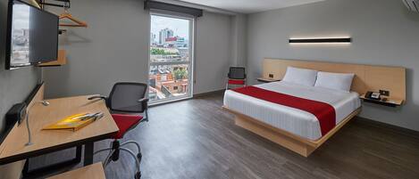 Una habitación de hotel moderna con cama, escritorio, silla y televisor.