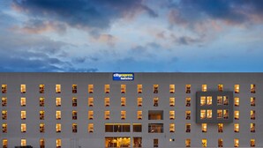 Un bâtiment d'hôtel avec une enseigne indiquant « cityexpress hotels » et de nombreuses fenêtres illuminées.