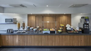 Un comptoir de buffet proposant divers plats, une machine à café et un four à micro-ondes.