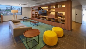 Un salon moderne avec un canapé, des poufs, une table basse et un téléviseur.