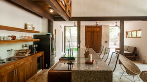 Una cocina amplia con armarios de madera, encimera de granito y una zona de estar con sillas de mimbre.