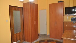 Una habitación con armarios de madera, televisor y una alfombra estampada.