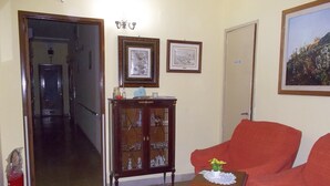 Una sala de estar con un sofá rojo, un mueble de madera con puertas de cristal y dos cuadros en la pared.