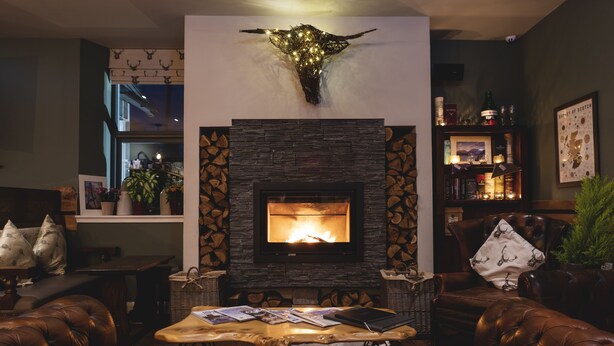 A cozy living room with a fireplace, leather sofas, and a stone fireplace surround.