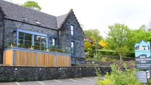 A stone building with a wooden deck and a sign for Ben Cruachan Inn.
