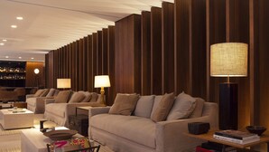 A modern living room with two sofas, a coffee table, a side table with a lamp, and a bookshelf in the background.