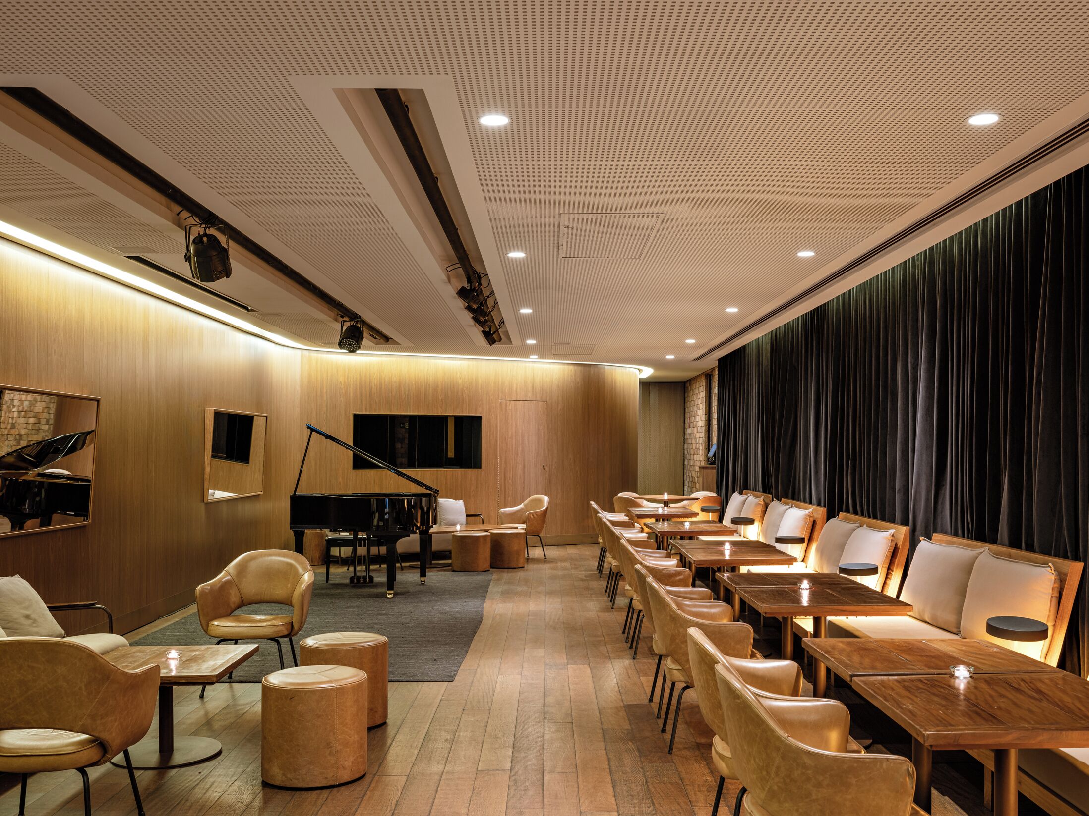 Una habitación de hotel con un piano, un escenario y un área de estar con mesas y sillas.