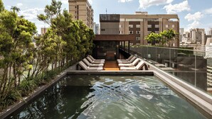 A rooftop pool area with lounge chairs, a small pool, and a view of surrounding buildings.