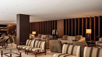 A modern lobby with striped sofas, a bar area, and wooden panel walls.