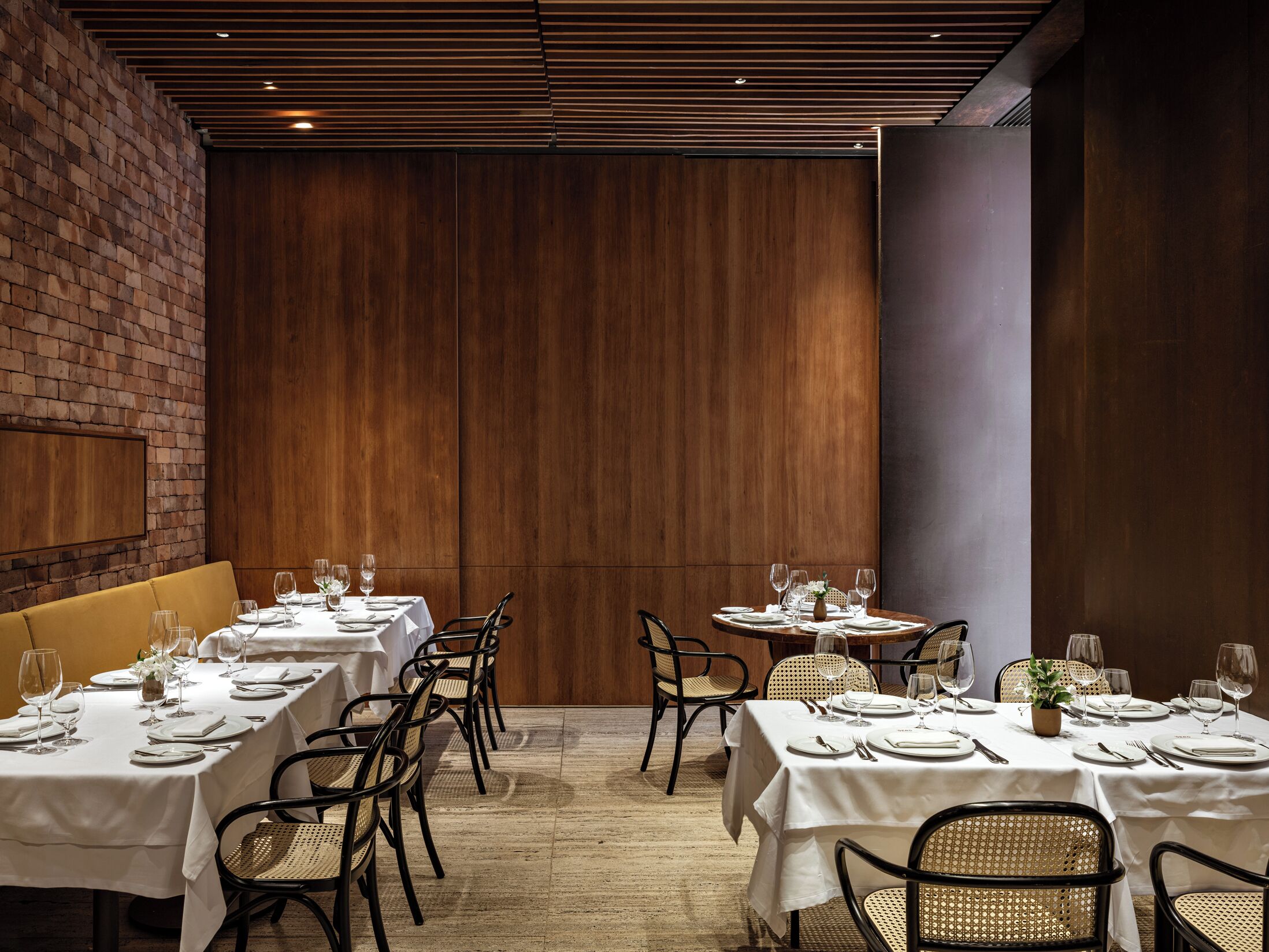 A restaurant with multiple tables set for dining, featuring a mix of wooden and upholstered chairs.