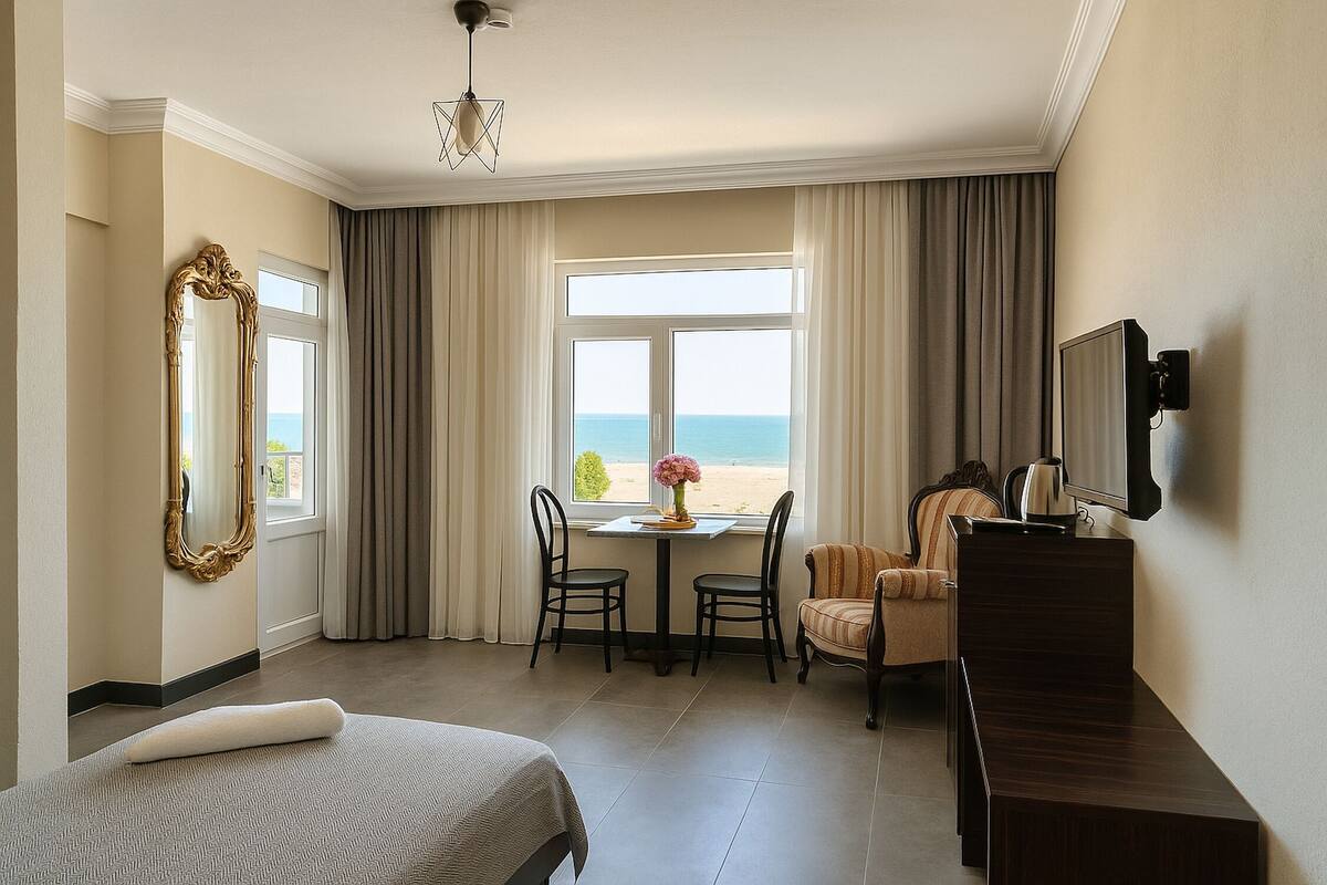 Ein Hotelzimmer mit Bett, Schreibtisch, Stuhl, Tisch mit Vase und Meerblick.