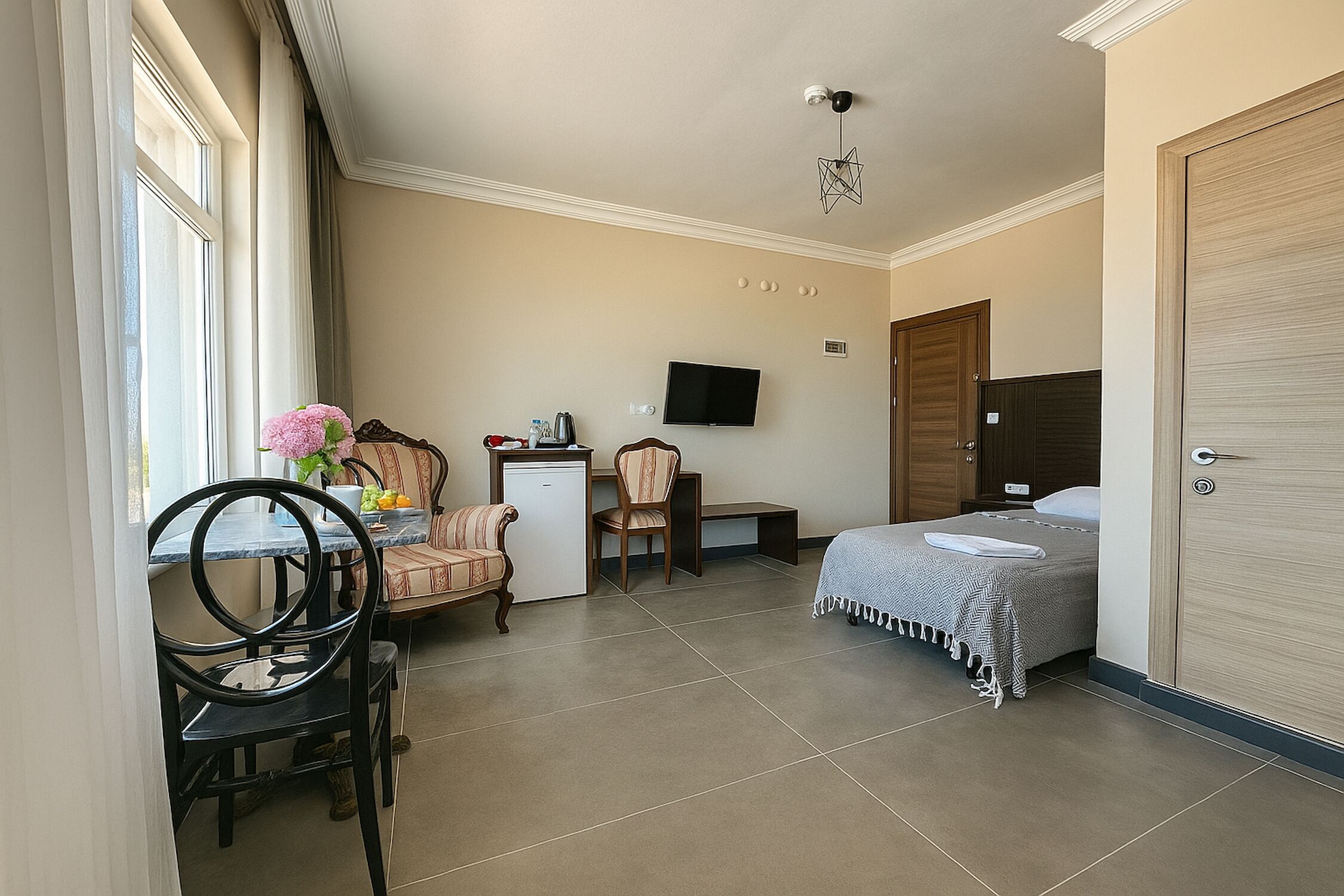 A compact room with a bed, a desk with a computer, a chair, and a television.