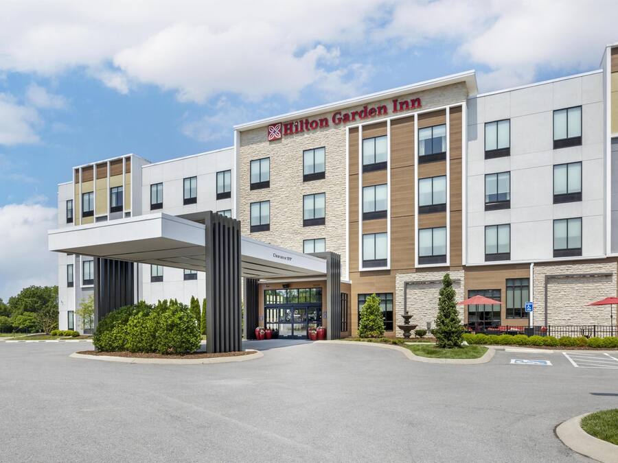 Um moderno Hilton Garden Inn com entrada ampla, vários andares e céu claro.