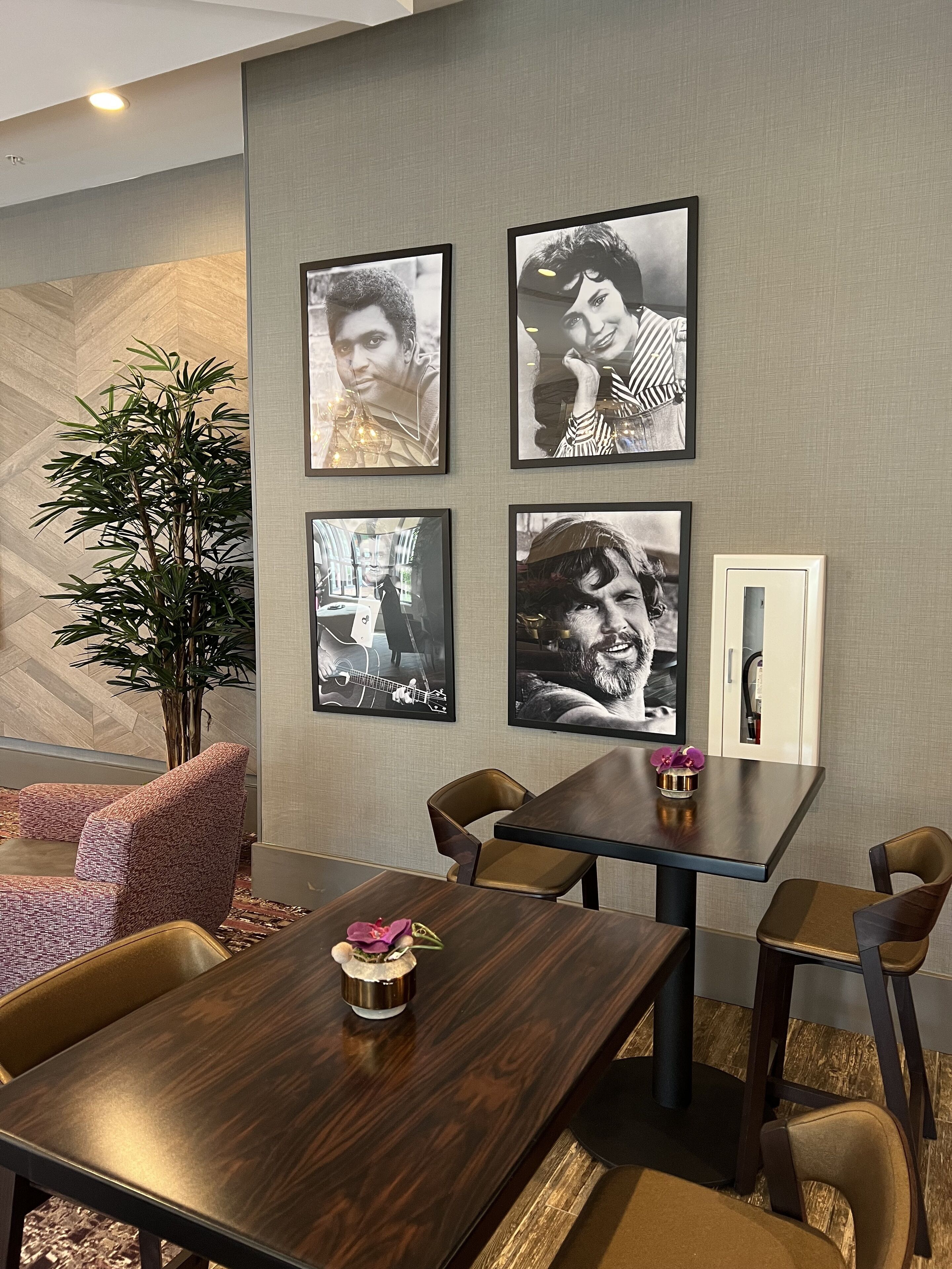 A modern dining area with a wooden table, cushioned chairs, and framed artwork on the wall.