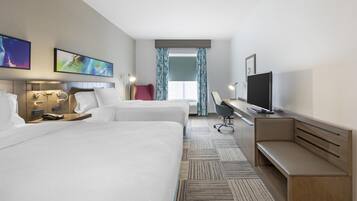 Una habitación de hotel con dos camas, un escritorio, un televisor y obras de arte en las paredes.