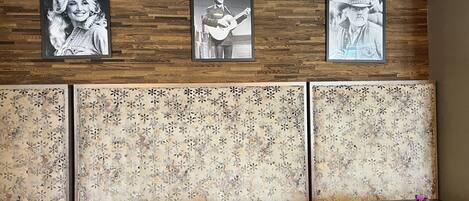 A restaurant with wooden panel walls, framed black and white photographs, and a floral patterned back wall. Tables and chairs are arranged for dining.