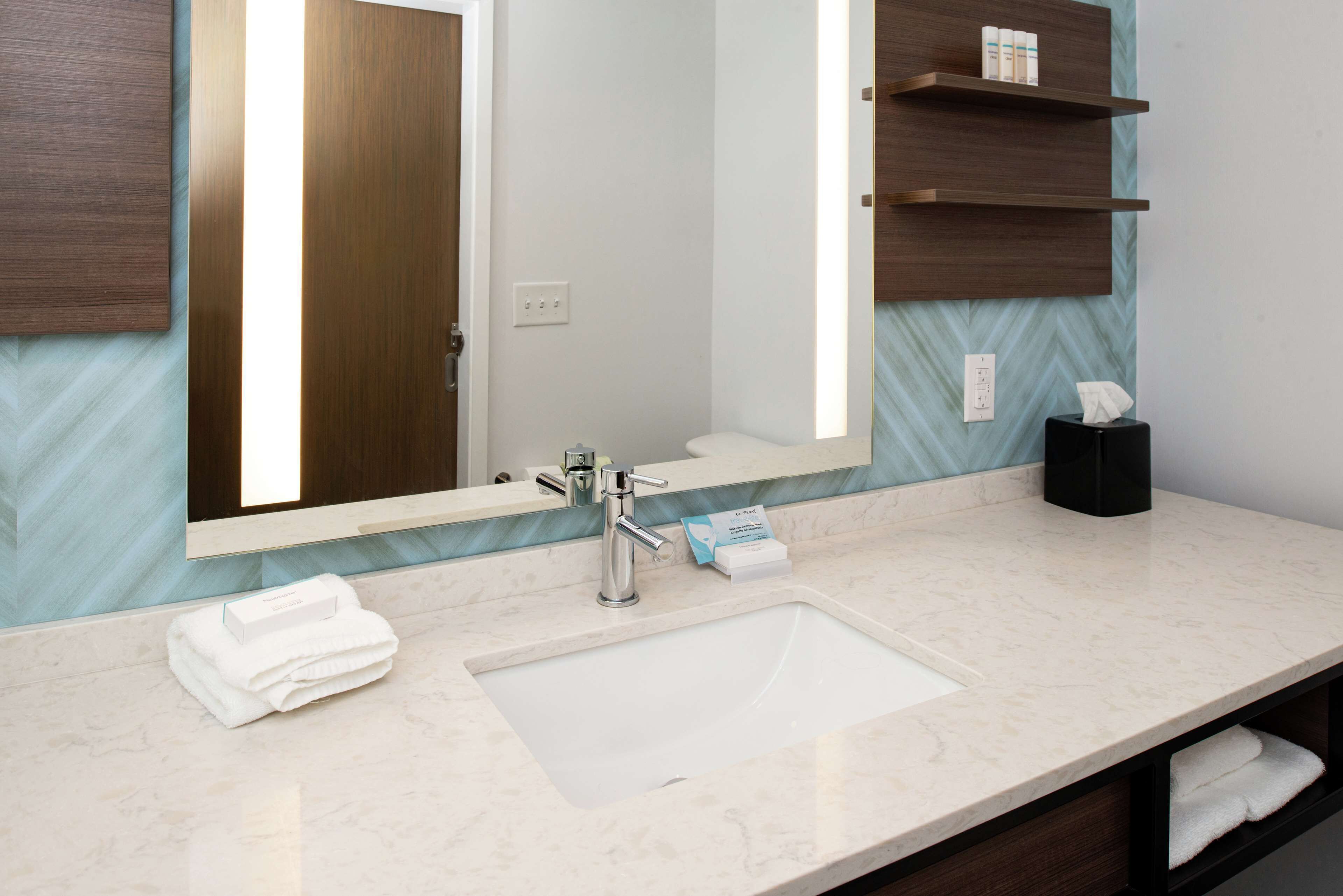 Une salle de bain avec un grand miroir, un lavabo et un porte-serviettes.